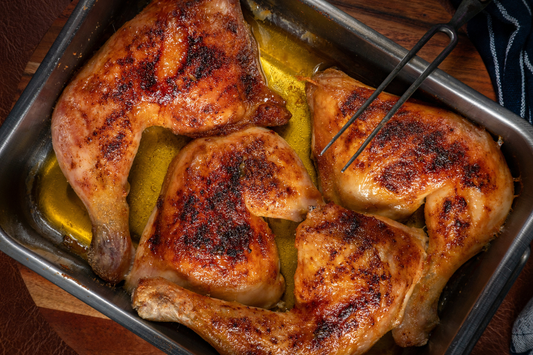 Roasted chicken leg quarters in a baking tray on a wooden surface