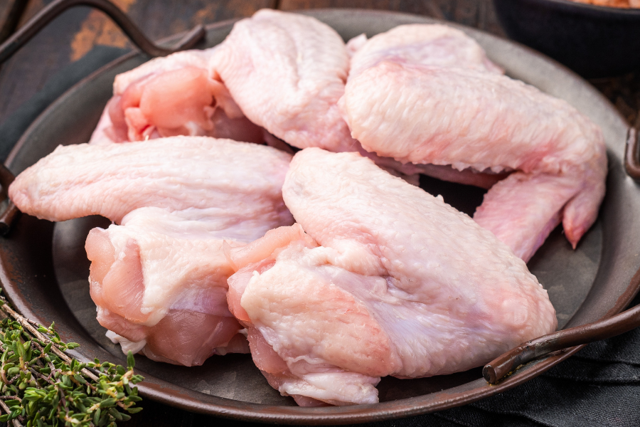 Raw local chicken wings on a dark plate, pasture-raised, non-GMO