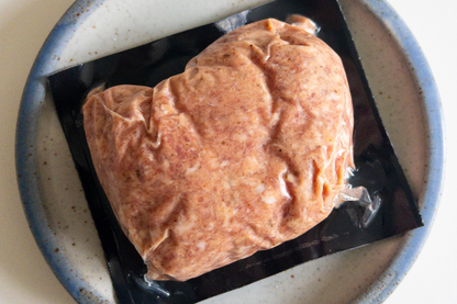 Raw local NC farm pasture raised pork sausage package on a speckled ceramic plate