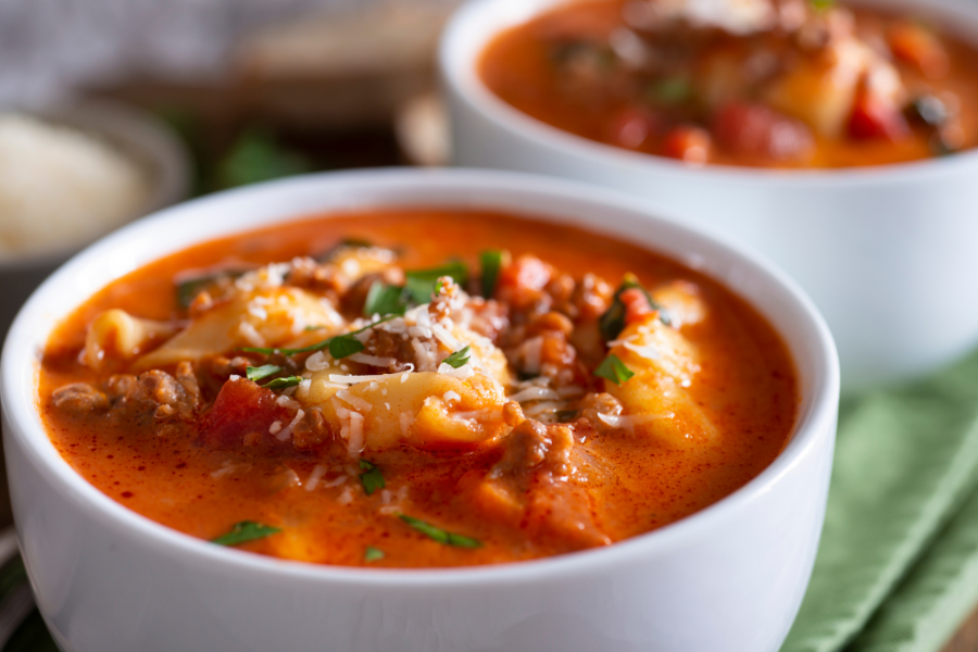 Two bowls of pasture raised pork chorizo sausage soup with pasta and greens on a green napkin.