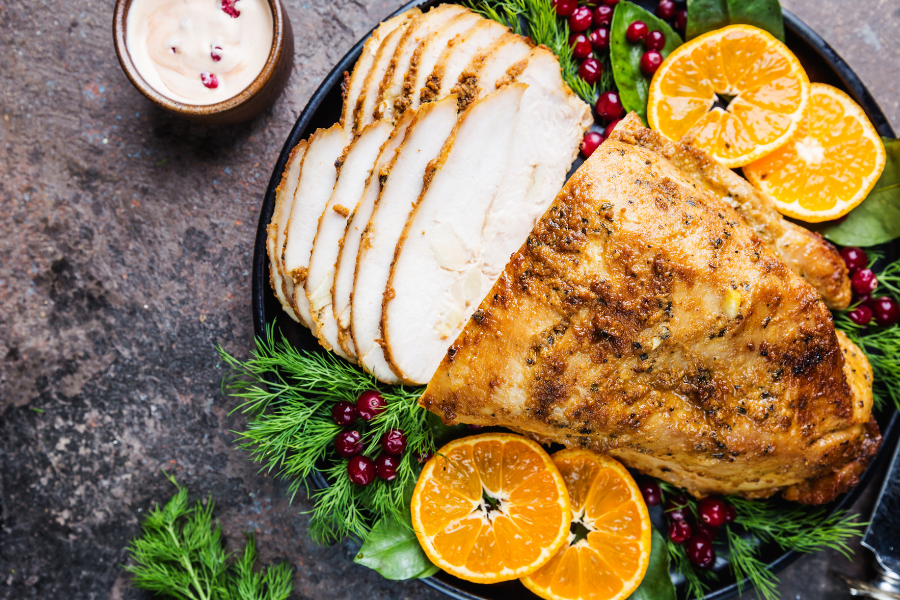 Non-GMO boneless skinless turkey breast, roasted on a plate with orange slices 