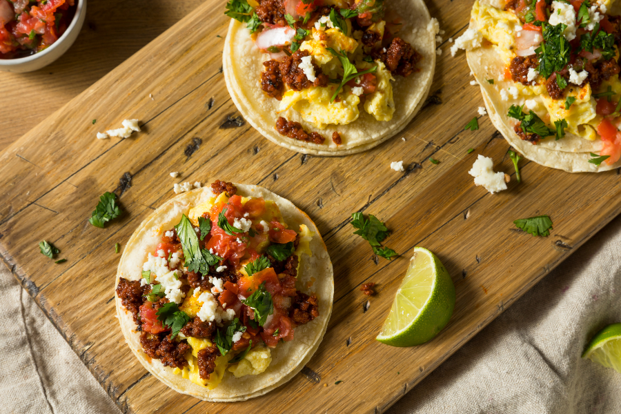 local forest raised pork chorizo breakfast tacos with eggs and toppings on a cutting board with lime