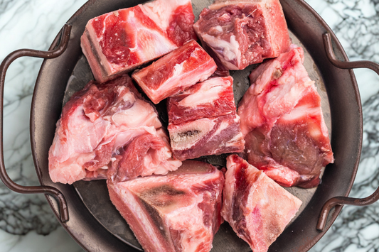 Dry aged beef soup bones, from our grass-fed beef farm, in a metal pan on a marble surface