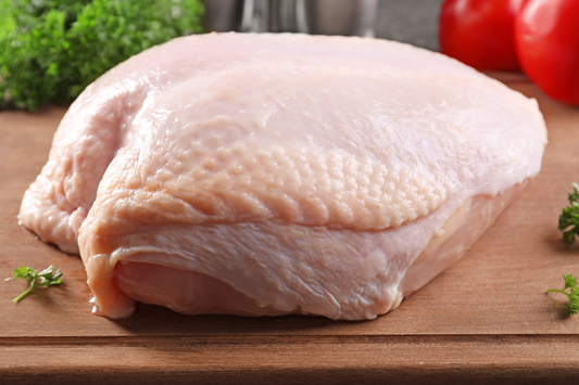 Raw bone-in pasture raised turkey breast,  with skin on a cutting board, non-GMO, NC farm fresh turkey