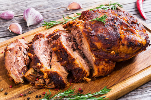 Pasture raised pork shoulder cooked and sliced on a cutting board, local pork delivery